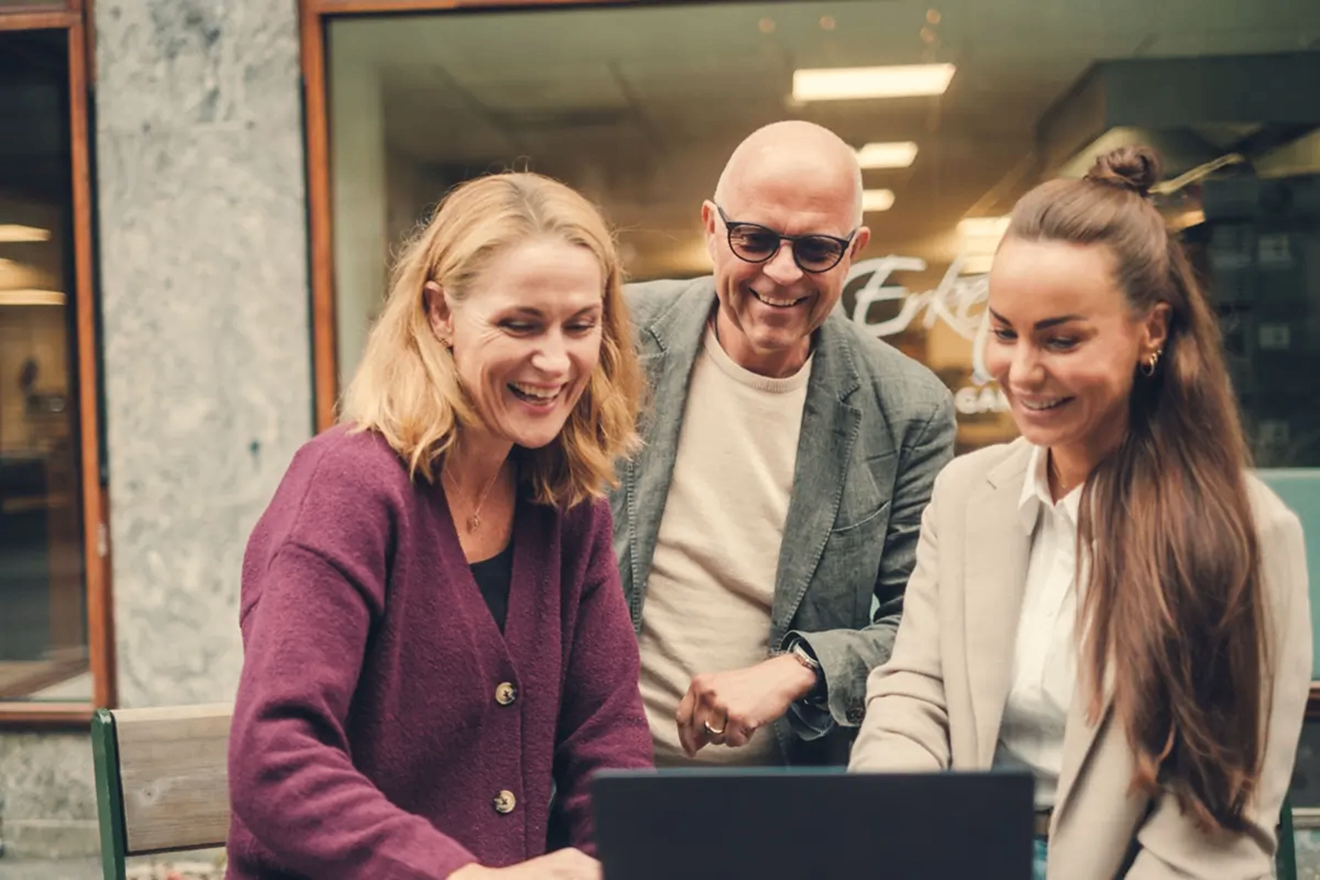 Omnium colleagues collaborating around a laptop outside the office