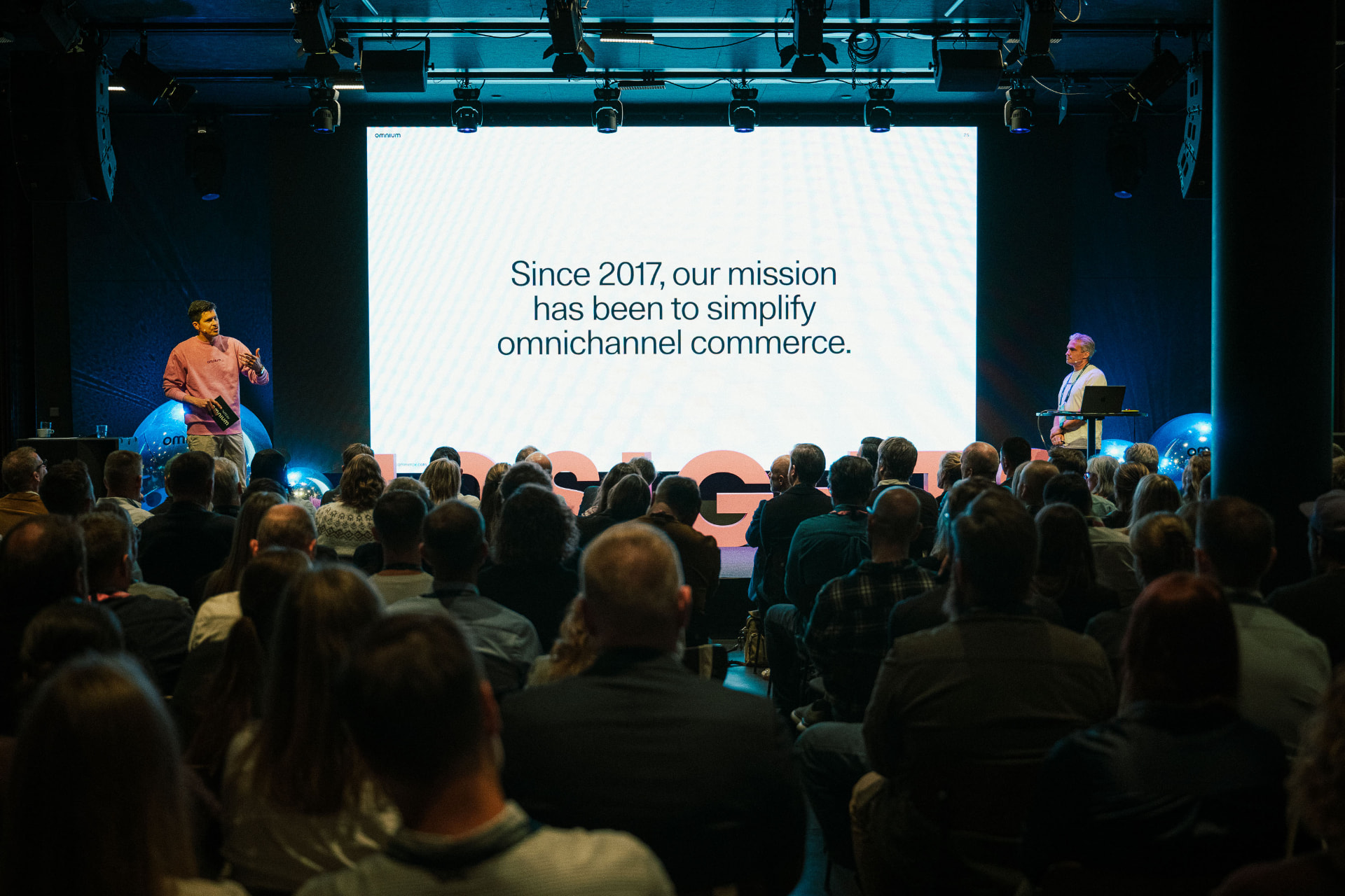 A speaker on the INSIGHTS by Omnium stage presenting to a full auditorium